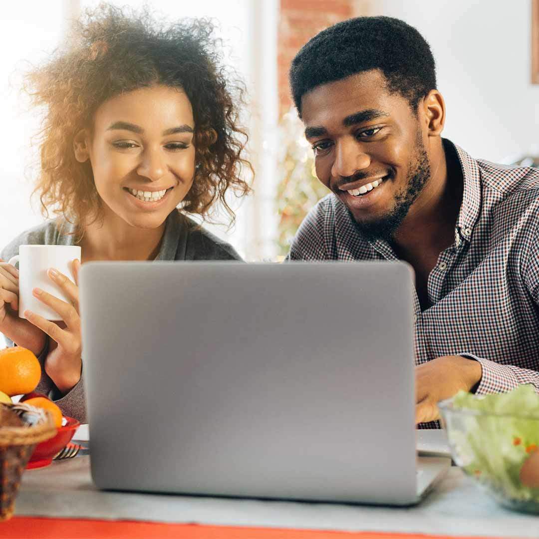 black couple at kitchen table looking at computer